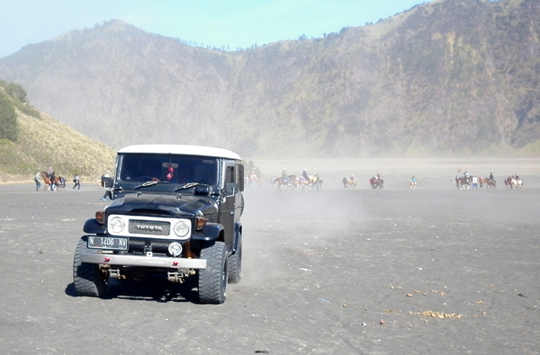 View across the 'Sea of Sand' in the caldera at Mt Bromo Example of Immaculate FJ 40 4WD with ponies behind and Caldera Rim in Distance.